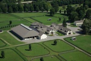 an arial view of a large horse farm with barns, arena, roads, and grassy paddocks